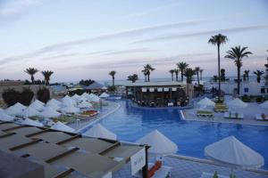 un complejo con una piscina con sombrillas blancas y palmeras en Bungalow de Luxe en Bord de Mer a Nabeul, en Douane