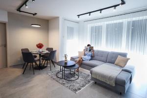 a woman sitting on a couch in a living room at Drill Residence Apartments in Kisvárda