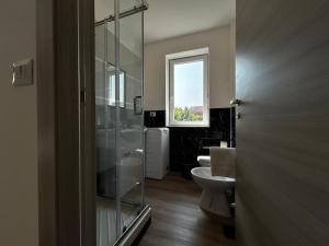 a bathroom with a toilet and a sink and a window at Catullo Lounge and Rooms Near The Airport in Caselle