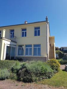a large white house with a staircase in front of it at Duplex les pieds dans l'eau in Grandcamp-Maisy +12 photos