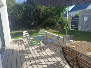 four chairs and a table and an umbrella on a deck at Maison de bord de mer - proche plage in La Turballe