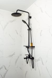 a shower head in a bathroom with white tiles at Къщи за гости БРИК in Sapareva Banya +27 photos