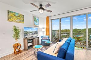 a living room with a blue couch and a tv at Resort Pool & Spa, Fitness Center, Pet Friendly, Waterfront Condo in Downtown! in Sarasota