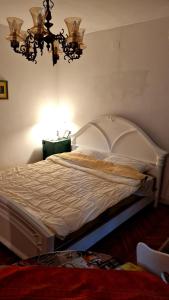 a bedroom with a large white bed with a chandelier at Antique Apartman in Mladenovac