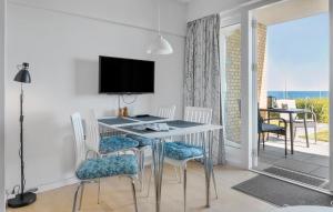 a dining room with a table with chairs and a television at Cozy Apartment In Allinge With Wifi in Allinge