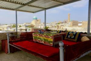 a bed on a balcony with a view of a city at Sarrof Guest House in Bukhara