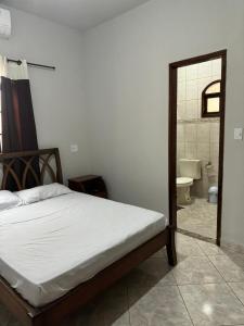 a bedroom with a bed and a bathroom with a toilet at Casa em São Pedro da Aldeia - RJ in São Pedro da Aldeia