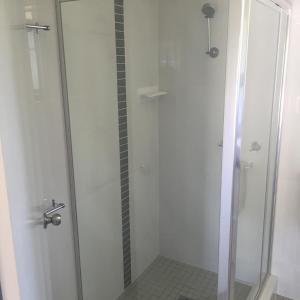 y baño con ducha blanca y puerta de cristal. en Macquarie Valley Motor Inn en Warren