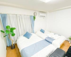 大阪市にある新大阪駅近く A1 Guest House ユニオン新大阪,リーズナブルで長期滞在にも最適のベッド2台と壁掛け時計が備わる客室です。
