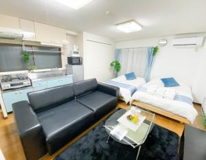 大阪市にある新大阪駅近く A1 Guest House ユニオン新大阪,リーズナブルで長期滞在にも最適のベッド2台とソファのあるリビングルーム
