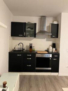 a kitchen with black cabinets and a stove at Stilvolle Wohnung in Offenburg in Offenburg