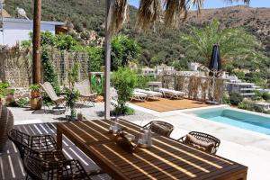 a patio with a table and chairs and a swimming pool at South Palms luxury village house in Áno Rodhákinon