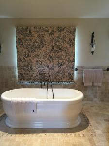a bath tub in a bathroom with a wall at Collins Cottage in Bright