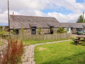 una vecchia casa in pietra con un tavolo da picnic nel cortile di Horseshoe Cottage a Bideford
