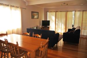 a living room with a table and a couch and a television at Corinda Cottage - 4 bedroom pet friendly in Bright