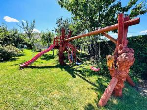 a playground with a red slide in the grass at Sowi domek in Płaska