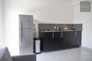 a kitchen with black cabinets and a refrigerator at KRONOS APARTMENTS in Paramaribo