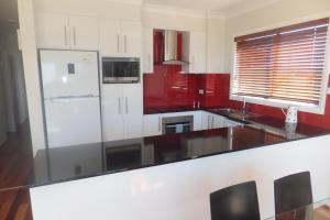 a kitchen with a white refrigerator and red cabinets at Ocean Retreat in Nambucca Heads +20 photos
