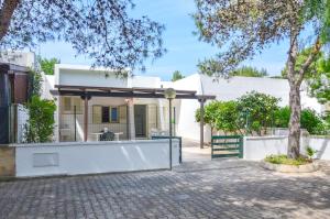 a white house with a fence and a tree at Villetta Pinetata 452 in Ugento