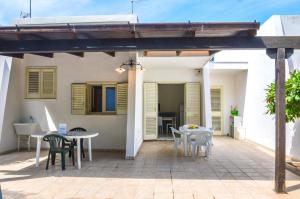 a patio with tables and chairs and a house at Villetta Pinetata 452 in Ugento