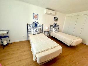 two beds in a room with wooden floors at Akonxego&Cia in Mourão