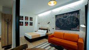 a bedroom with a bed and a orange couch at Aparthotel Luz de Gades - Suites Spa Gym - Adults Only in Cádiz +37 photos