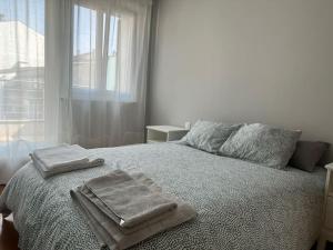 a bedroom with two towels on a bed with a window at Increíble dúplex en Lugo in Lugo