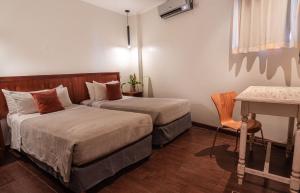 a hotel room with two beds and a table at Hotel Saint George in Puerto Iguazú