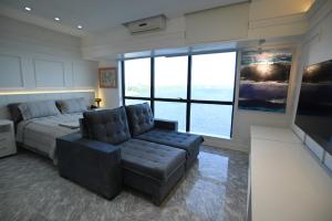 a bedroom with a bed and a couch and a large window at Tropical Executive Flat Suite 817 with View in Manaus