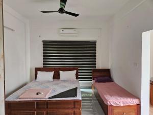 a bedroom with two beds and a ceiling fan at Yogis Inn in Kozhikode