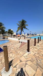 a resort with a swimming pool and palm trees at Residencial Marina clube D205 in São Pedro da Aldeia