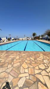 a swimming pool with a stone floor and blue sky at Residencial Marina clube D205 in São Pedro da Aldeia
