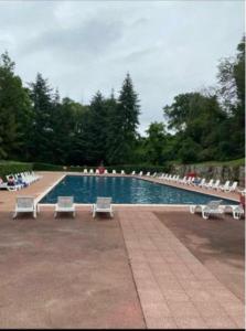 a swimming pool with lounge chairs and a group at Mobil home in Saint-Chéron +2 photos