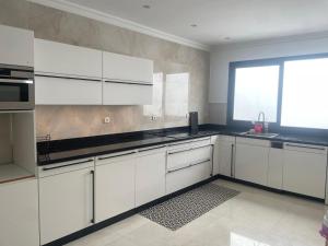 a kitchen with white cabinets and a window at Residence wassim in Ras El Ma