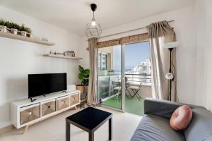a living room with a couch and a tv and a balcony at Apto Sol Paraiso Sunset View in Adeje