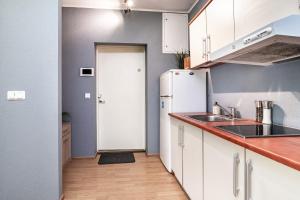 a kitchen with white cabinets and a white refrigerator at Peaceful studio with desk & free parking near city center in Tallinn