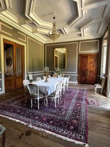 a dining room with a table and chairs on a rug at Château de Laclaireau in Virton