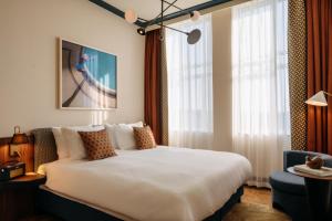 una camera da letto con un grande letto bianco e finestre di De Plesman Hotel The Hague a L'Aia