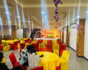 a large room with yellow tables and red chairs at The Crown Hotel Agra near Taj Mahal in Agra