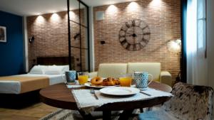 a room with a table with a plate of food and a clock at Aparthotel Luz de Gades - Suites Spa Gym - Adults Only in Cádiz