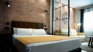 a bedroom with a large bed and a brick wall at Aparthotel Luz de Gades - Suites Spa Gym - Adults Only in Cádiz