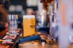 a glass of beer sitting on top of a table at The Fox Den in Reading