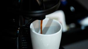 a coffee is being poured into a coffee cup at Aparthotel Luz de Gades - Suites Spa Gym - Adults Only in Cádiz