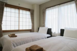 two beds in a room with two towels on them at Hotel Imalle Haneda in Kawasaki
