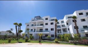 a white building with palm trees in front of it at Casas del mar cabo in Cabo Negro