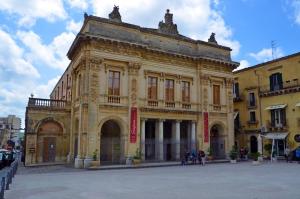 a large yellow building with people standing in front of it at Casa Michela in Noto