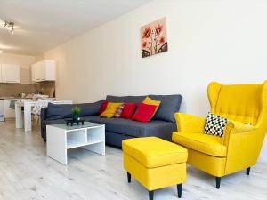 a living room with a blue couch and yellow chairs at Seaside Apartment in Varna City