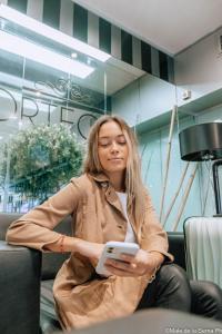 a woman sitting on a chair holding a tablet at Hotel Ortegal in Mar del Plata