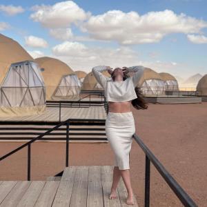 a woman in a dress looking up at the sky at Rum Leno Luxure camp in Wadi Rum
