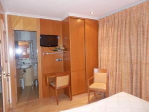 a room with a table and a television and a bathroom at Hotel Restaurante Salvadora in Villena